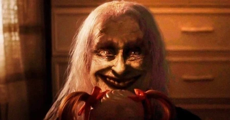 Entidade demoníaca sorri de forma macabra enquanto segura a boneca Annabelle em Invocação do Mal 4 (2026)