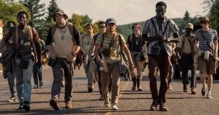 Grupo de jovens participantes caminha exausto sob o sol em cena de A Longa Marcha – Caminhe ou Morra (2025)